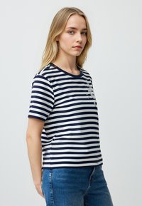 Marineblauwe en witte gestreepte t-shirt, korte mouwen, ronde halslijn, met een bloemenapplicatie op de borst, gemaakt van lichte stof.