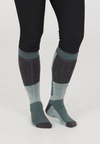 Polvisukkia, joissa yhdistyvät teal- ja tummanharmaat värit, joustavaa pintaa ja geometrisia kuvioita sääressä.