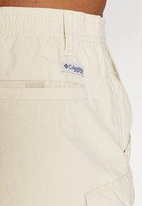 Lyse beige shorts lavet af blødt stof, med en elastisk talje og et Columbia-logo. Designet med sidelommer og minimale sømme.