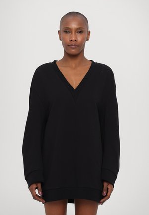 Musthave suur suurusega musta dressipluusi stiilis kleit sügava V-kaelusega, pikkade varrukatega ja ribidega mansettidega. Sile tekstuur ja minimaalne brändingu detail õlavarre peal.