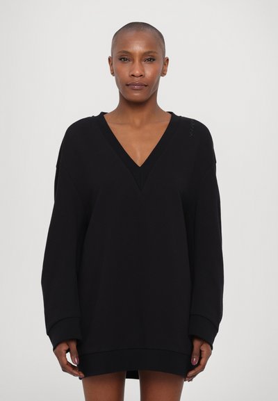 Vestido sudadera negro de gran tamaño con un profundo escote en V, mangas largas y puños acanalados. Textura suave con un mínimo detalle de marca en el hombro.