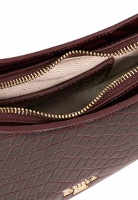 Burgundy textured leather bag with gold zippers and a beige lined interior, featuring two zippered compartments for organized storage.
