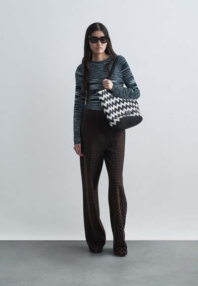 Μαύρη και άσπρη τσάντα tote σε σχέδιο καρό, εφαρμοστή ριγέ μπλούζα με μακριά μανίκια, καφέ φαρδιές παντελόνες με σχέδιο. Λείο ύφασμα, άνετη εφαρμογή και μονοχρωματικό σχέδιο.