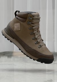 Brązowe skórzane buty górskie z szarymi akcentami, wyściełanym kołnierzem, metalowymi oczkami i teksturowaną podeszwą. Zawierają logo na boku.
