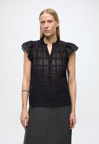 Svart bluse med pufferm og teksturert, rutete mønster, med delvis knappestolpe og rund hals.