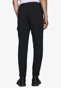 Dunkelgraue, taillierte Hose mit Slim-Fit, umgeschlagenen Säumen, seitlichen Taschen und geknöpften Gesäßtaschen, aus einem strukturierten Wollmischgewebe.