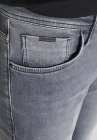 Jeans in denim grigio scuro con una finitura testurizzata, dotati di una tasca posteriore e di un piccolo etichetta nera con la scritta "ANTHONY MORATO."