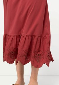 Bordeauxfarbene Baumwollrock mit einem gerafften Saum, der mit kunstvollen gestickten Blumenmustern und Ausschnittdetails am unteren Rand verziert ist.