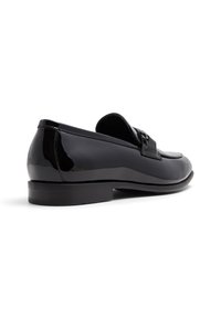 Svarta lackskinnsloafers med en slip-on design, som har ett framvarande band och en låg klack. Slät textur och rund tåform.