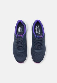 Navy mesh athletic shoes with purple accents, featuring a flexible sole and lace-up design. Model name "ArchFit" on the insole.