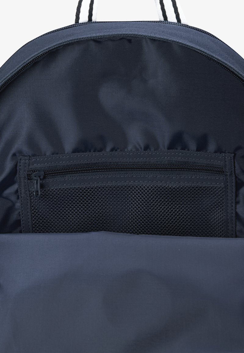 Interior de mochila azul marino con un forro de tela suave. Cuenta con un bolsillo de malla con cremallera para organización y opciones de almacenamiento adicionales.
