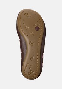 Suela de zapato sintético marrón con una superficie texturizada, que presenta patrones elevados y acentos en forma de burbujas. Un caucho de color claro contornea los bordes.