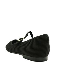 Zapato plano Mary Jane de tela negra acanalada con punta redonda y tira con hebilla plateada, vista en ángulo que muestra el talón y el lateral.