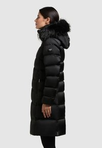 Mustad sulejope võltskarvaga kapuutsiäärega, tikkimismustriga, küljetaskute ja logomärgiga ülemisel käel. Soe ja keskmise pikkusega stiil.