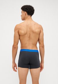 Boxer-briefs pour hommes en gris foncé avec une ceinture bleue. Le tissu semble lisse et extensible, avec un design ajusté.