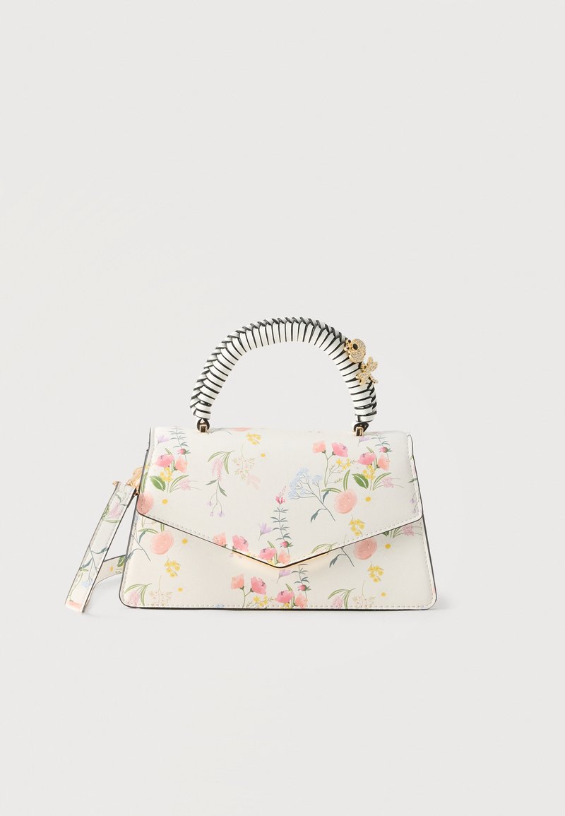 Sac à main blanc fleuri avec une anse rayée enveloppée et un ornement doré en forme d'abeille sur un fond uni.