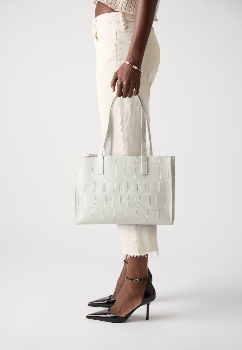 Hellgrüne Handtasche mit Krokodilprägung und dem Logo "TED BAKER LONDON", ausgestattet mit zwei oberen Traggriffen und einer strukturierten rechteckigen Form.