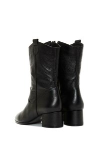 Botas de tobillo de cuero negro con un acabado texturizado, punta redondeada y un tacón bajo y cuadrado. Cuenta con una cremallera lateral y una lengüeta decorativa.