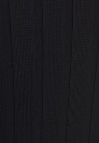 Lähikuva mustasta ribbikudumist, millel on vertikaalsed kõrged triibud, näidates üksikasjalikku tekstuuri.