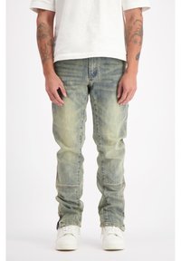 Lichtblauwe denim jeans met een vervaagd effect, slim fit en subtiele stiksels. Draagt met een plain wit t-shirt en witte sneakers.