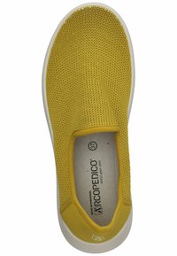 Chaussure slip-on tricotée jaune avec une semelle blanche et un bout rond, présentant un dessus texturé et une étiquette à l'intérieur avec les détails de taille.