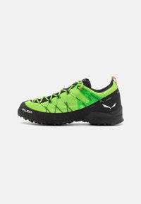 Chaussure d'extérieur verte et noire avec une tige texturée, un embout en caoutchouc durable et un système de laçage. Caractéristiques d'une semelle extérieure antidérapante et d'un talon renforcé.