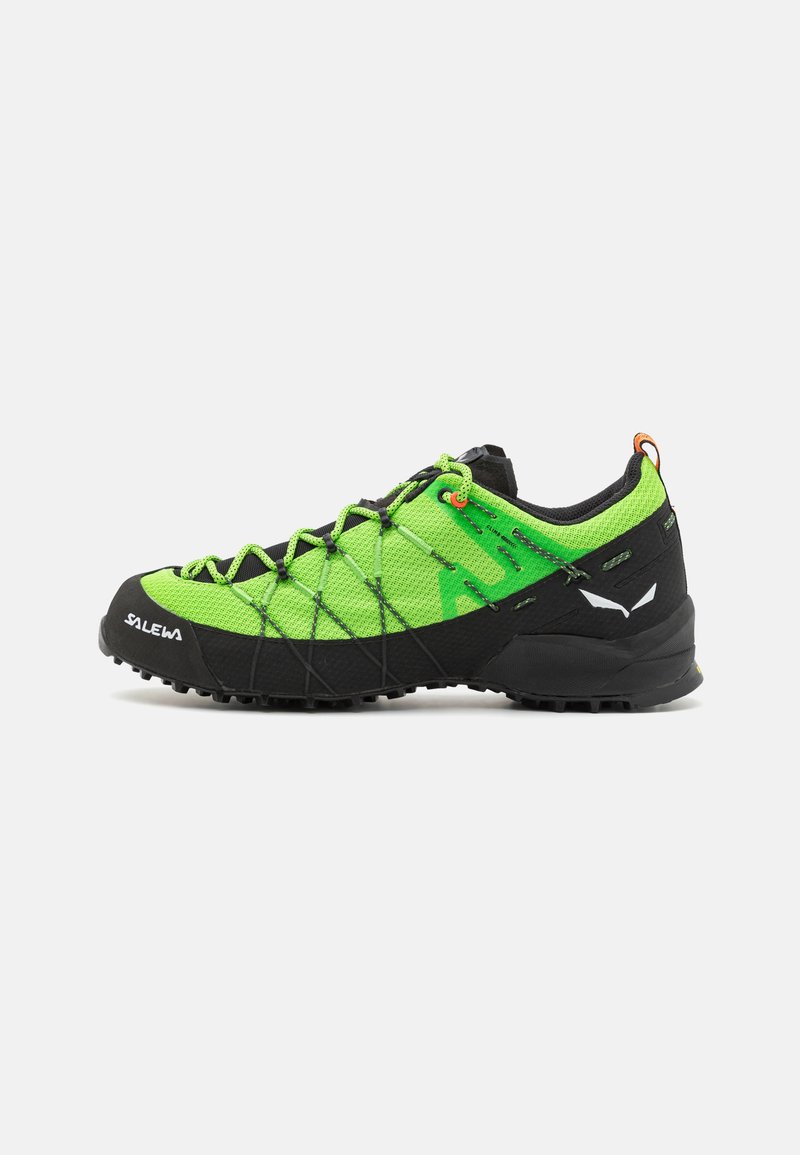 Chaussure d'extérieur verte et noire avec une tige texturée, un embout en caoutchouc durable et un système de laçage. Caractéristiques d'une semelle extérieure antidérapante et d'un talon renforcé.