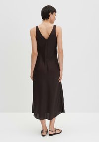 Abito maxi marrone senza maniche con design a V sulla schiena, realizzato in materiale morbido, caratterizzato da una leggera svasatura e fessure laterali all'orlo.