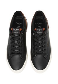 Zapatillas de cuero negro con diseño de corte bajo, suela de goma blanca, puntera redonda y detalles marrones en el cuello y la lengüeta.