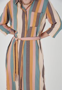 Gestreiftes Hemdkleid in Pastellfarben mit tailliertem Gürtel, ausgestattet mit einer Brusttasche und Dreiviertelärmeln. Hergestellt aus einem weichen, strukturierten Stoff.