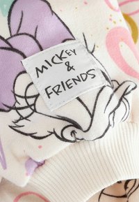 Valge puuvillane kangas, millel on pastelltoodetes karikatuuride illustreerimised. Sildiga "Mickey & Friends", mis on õmmeldud. Nähtav ribikant.
