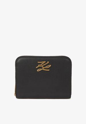 Portefeuille en cuir noir avec quincaillerie dorée. Présente une texture lisse et un logo en relief sur le devant. Forme rectangulaire avec fermeture éclair.