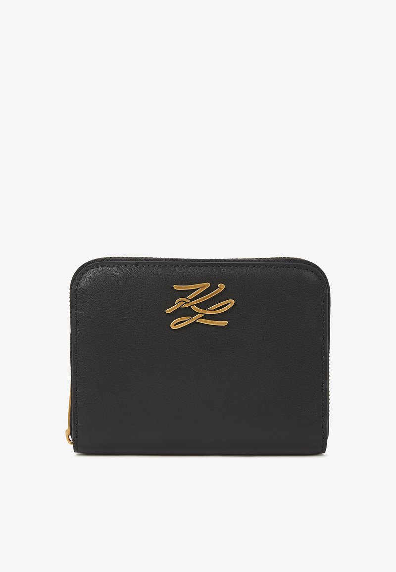 Carteira de couro preto com ferragens douradas. Apresenta uma textura suave e um logotipo em relevo na parte da frente. Forma retangular com fecho de zíper.