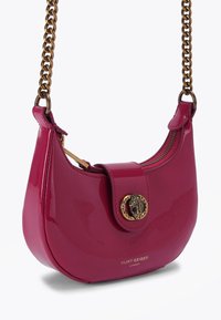 Borsa a mano in pelle verniciata magenta con forma rotonda, tracolla in catena color oro, chiusura con zip e un bottone decorativo con accenti neri.