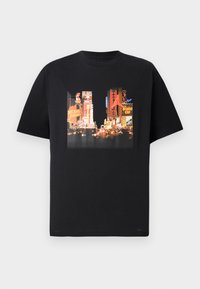 Melns T-krekls ar dzīvīgu Times Square apdruku, kas ietver krāsainus reklāmas materiālus, tostarp "Michael Jordan" un "Nike". Īsas piedurknes, apaļa kakla izgriezums.