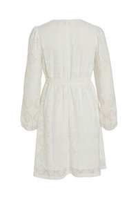 Λευκό φόρεμα δαντέλας με μακριά μανίκια, εφαρμοστή μέση και υφή σε διαμαντόσχημο σχέδιο. Στο πίσω μέρος έχει στρογγυλή λαιμόκοψη και ραμμένα διακοσμητικά στοιχεία.