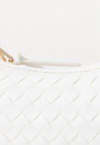 Λευκή τσαντάκι χειρός από υφαντό υλικό με λεία υφή, κλείσιμο με φερμουάρ και εξαρτήματα σε χρυσό τόνο. Κομψός σχεδιασμός με λεπτομέρειες πλεξίματος.