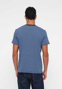 Sinine ja valge triibuline lühikeste varrukatega T-särk, puuvillane materjal, ümmargune kaelus, millel on vabalt langev lõige ja nähtavad õmblused seljal.