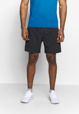 Grå sportshorts med elastisk midjeband, i kombination med en blå t-shirt med kort ärm och vita sportskor. Slät tygstruktur.