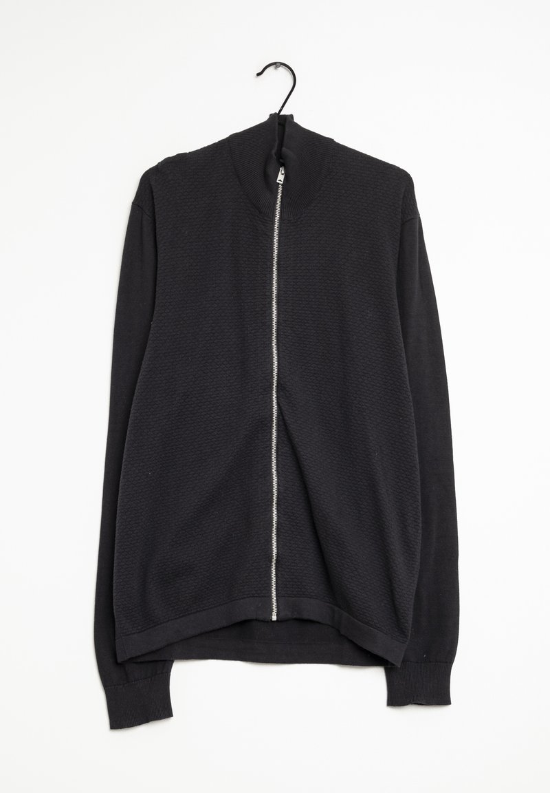 Svart zip-up jacka med ett strukturerat mönster, hög krage och långa ärmar. Tillverkad av ett mjukt, stickat material. Hänger på en krok.