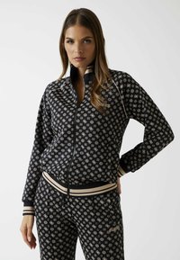 Zwarte jas met rits gemaakt van gladde stof, met een geometrisch patroon in beige, contrasterende gestreepte manchetten en kraag, smal gesneden model.