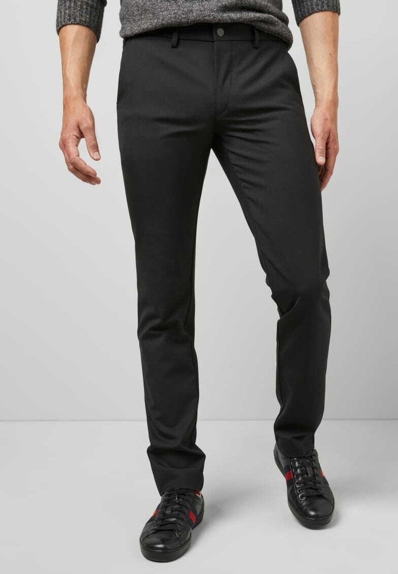 Zwarte broeken met een slim fit, gemaakt van een gladde stof. Voorzien van een knoopsluiting, riemlussen en zijzakken. Gecombineerd met zwarte sneakers.