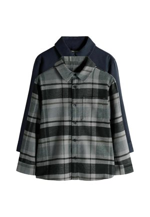 Grau kariertes Flanellhemd mit langen Ärmeln, Knopfverschluss und Brusttasche, über einem marineblauen Hemd mit Knopfverschluss getragen.