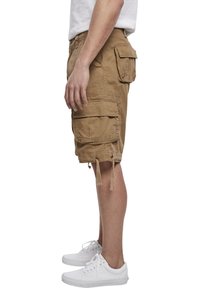 Shorts cargo kaki avec plusieurs poches spacieuses, coupe décontractée, et ourlets à cordon ajustable, assortis à des baskets blanches.