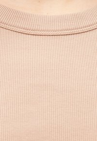 Hellrosa geripptes Top mit rundem Ausschnitt, das schmale vertikale Linien und eine glatte Textur aufweist. Der Stoff ist weich und leicht dehnbar.