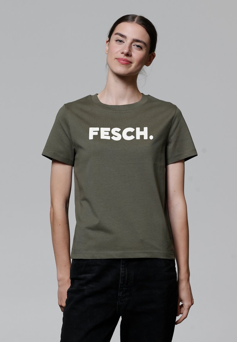 Olivgrünes T-Shirt mit kurzen Ärmeln aus Baumwolle, das auf der Vorderseite einen weißen Blockdruck mit "FESCH." und einen runden Halsausschnitt hat.
