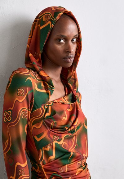 Hooded dress in vibrant orange, green, and gold patterns. Features a draped neckline and fitted silhouette with soft texture.