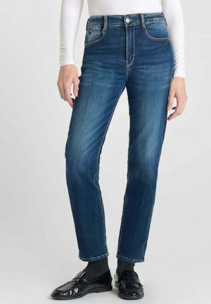 Jean en denim bleu foncé avec une coupe droite, présentant une taille haute, cinq poches et une finition légèrement délavée. Accentué par des coutures dorées.