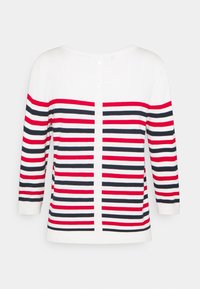 Raidallinen neuletakki valkoisena, punaisena ja tummansinisenä. Siinä on pitkät hihat, pyöreä pääntie ja nappikiinnitys takana, sekä pehmeä rakenne.