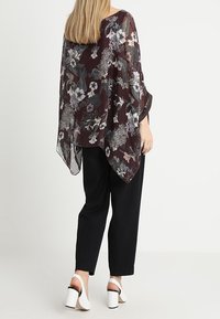 Przezroczysty, burgundowy kimono w kwiaty o luźnym kroju, z zaokrąglonym hemem i delikatnym wzorem kwiatowym, noszone na czarnych spodniach.